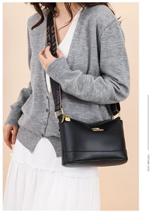 Detail of black pebbled leather handbag with jacquard strap and gold animal logo