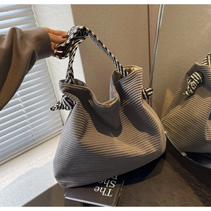 Detail of grey corduroy tote bag featuring unique black and white striped knot handles