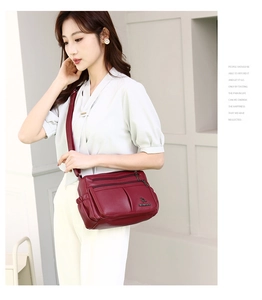Detail view of burgundy soft leather crossbody bag featuring multiple zippers and kangaroo logo