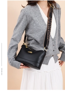 Close-up of black lychee leather bag with golden kangaroo logo and wide printed strap