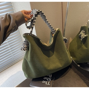 Detail of green corduroy tote bag featuring black and white diagonal striped handles