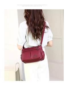 Detail view of burgundy leather crossbody bag featuring multiple zipper pockets and logo