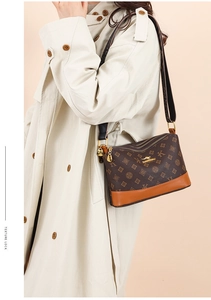 Detail view of the brown leather shoulder bag featuring multi-zipper layers and wide strap