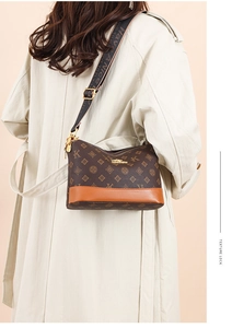 Close-up of soft leather brown monogram shoulder bag with wide textile strap