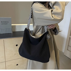 Detail of black corduroy tote bag featuring a stylish black and white striped shoulder strap