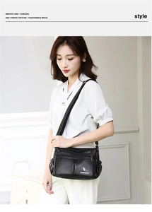 Detail of black faux leather crossbody bag with multiple zippers and gold kangaroo logo