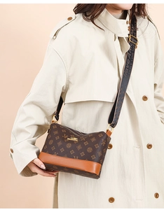 Detail of monogram leather crossbody bag with logo strap on beige trench coat