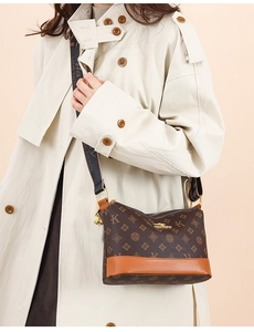 Detail of soft leather shoulder bag with dark brown monogram and wide textile strap