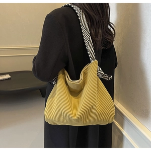 Detail of mustard corduroy tote bag with black and white striped shoulder strap