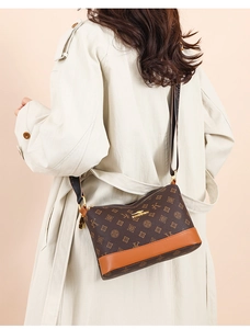 Close-up of brown faux leather shoulder bag with vintage pattern and gold logo
