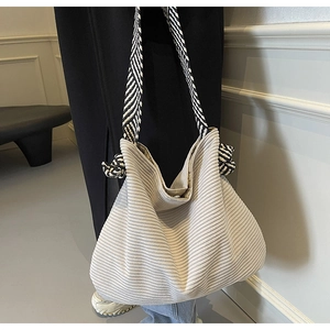Detail of corduroy tote bag featuring geometric woven strap and minimalist design