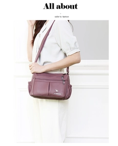 Detail view of purple leather crossbody bag with multiple zipper pockets and side pockets
