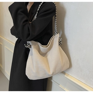 Detail view of cream corduroy tote bag with black and white braided rope straps