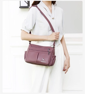 Detail of soft leather crossbody bag with multiple zip pockets and side elastic pouches