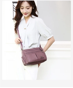 Close-up of soft leather texture and multi-layer zippers on this dark purple crossbody bag