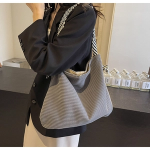 Detail of grey corduroy tote bag with black and white striped shoulder strap and soft texture
