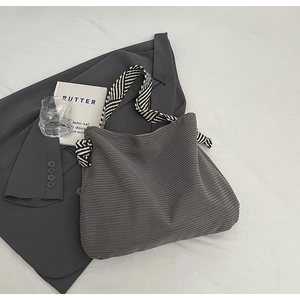 Detail of grey corduroy tote bag with black and white striped geometric pattern shoulder strap