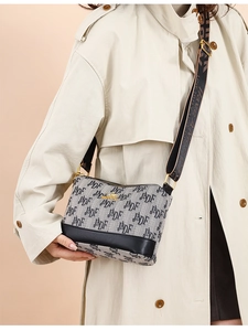 Detail of grey monogram canvas bag with black leather trim and wide jacquard strap
