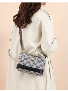 Close-up of jacquard fabric crossbody bag with adjustable wide strap on trench coat