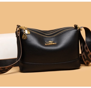Detail of black lychee leather bag with golden kangaroo logo and wide geometric strap