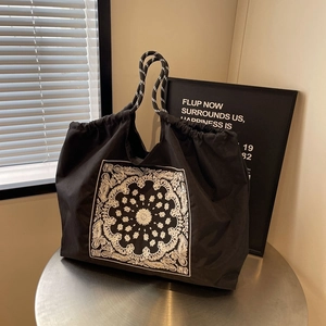 Black paisley embroidered nylon tote bag with drawstring closure and rope handles