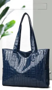 Detail of navy blue crocodile embossed tote bag with high-shine patent finish texture