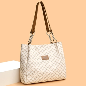 Off-white faux leather tote bag with brown geometric pattern and chain strap on podium