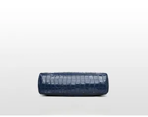 Detail view of the crocodile embossed glossy leather bottom of this blue tote bag