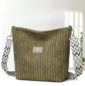 Detailed texture of olive green corduroy tote bag with patterned wide strap and patch