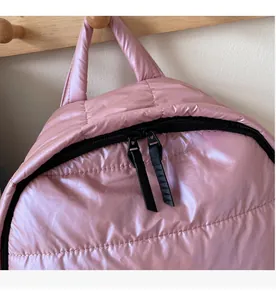 Detail of pink quilted puffer backpack featuring a smooth black double zipper closure