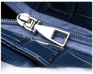 Detail of silver metal zipper on navy blue crocodile pattern faux leather tote bag