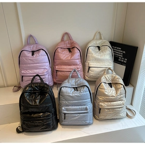 Detailed display of six quilted puffer backpacks in multiple colors on a tiered stand