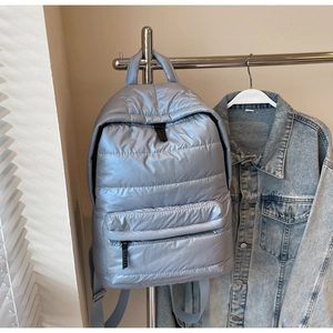 Close-up of light blue quilted padded backpack featuring high-shine metallic finish fabric