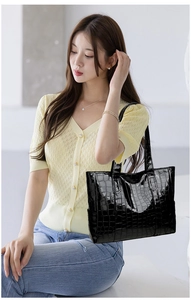 Close-up of black crocodile pattern tote bag held by model for commute lifestyle