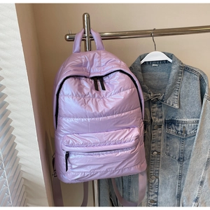 Detail of purple puffer backpack featuring quilted nylon texture and zipper pockets