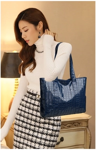 Detail of blue glossy crocodile pattern tote bag featuring long shoulder straps