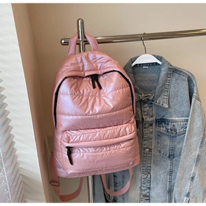 Close-up of pink quilted puffer backpack fabric and zipper detail on metal rack