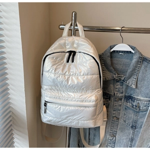 Detail of a white quilted puffer backpack with metallic finish and black zipper closure