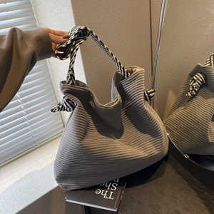 Gray corduroy tote bag with striped knotted handle shown in a minimalist room setting
