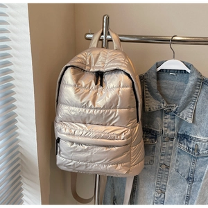 Detail of champagne gold quilted puffer backpack with metallic finish and black zippers