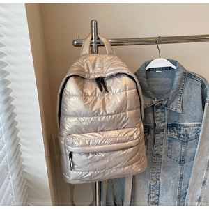 Detail of champagne gold quilted puffer backpack with shiny water-resistant texture