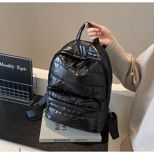 Close-up of black quilted puffer backpack featuring glossy waterproof nylon texture