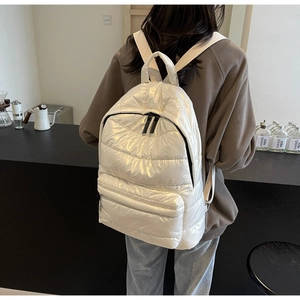 Rear view of a white puffer backpack worn in a cafe, showing quilted texture and capacity