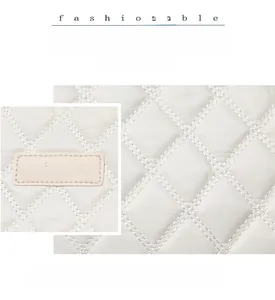 Gros plan sur le motif matelassé et le logo en cuir d'un grand sac fourre-tout blanc