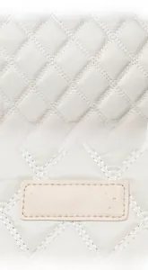 Gros plan du tissu matelassé beige avec coutures argentées et logo en cuir Perfect Lily