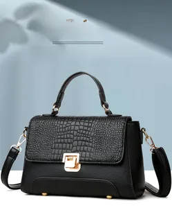 Detail of crocodile pattern flap and golden square lock on black leather crossbody bag