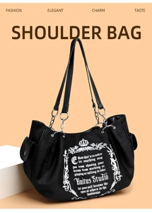 Detail of black canvas tote bag showing silver metal chain straps and crown print