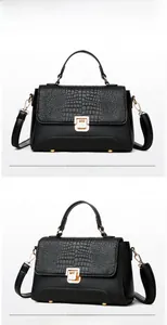 Detail of black faux leather handbag featuring crocodile pattern flap and golden lock
