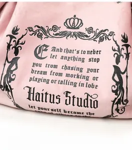 Detailed view of pink suede tote bag featuring black gothic print and soft texture