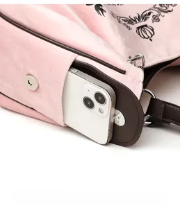Detail of pink velvet pumpkin bag featuring a magnetic clasp and black floral pattern